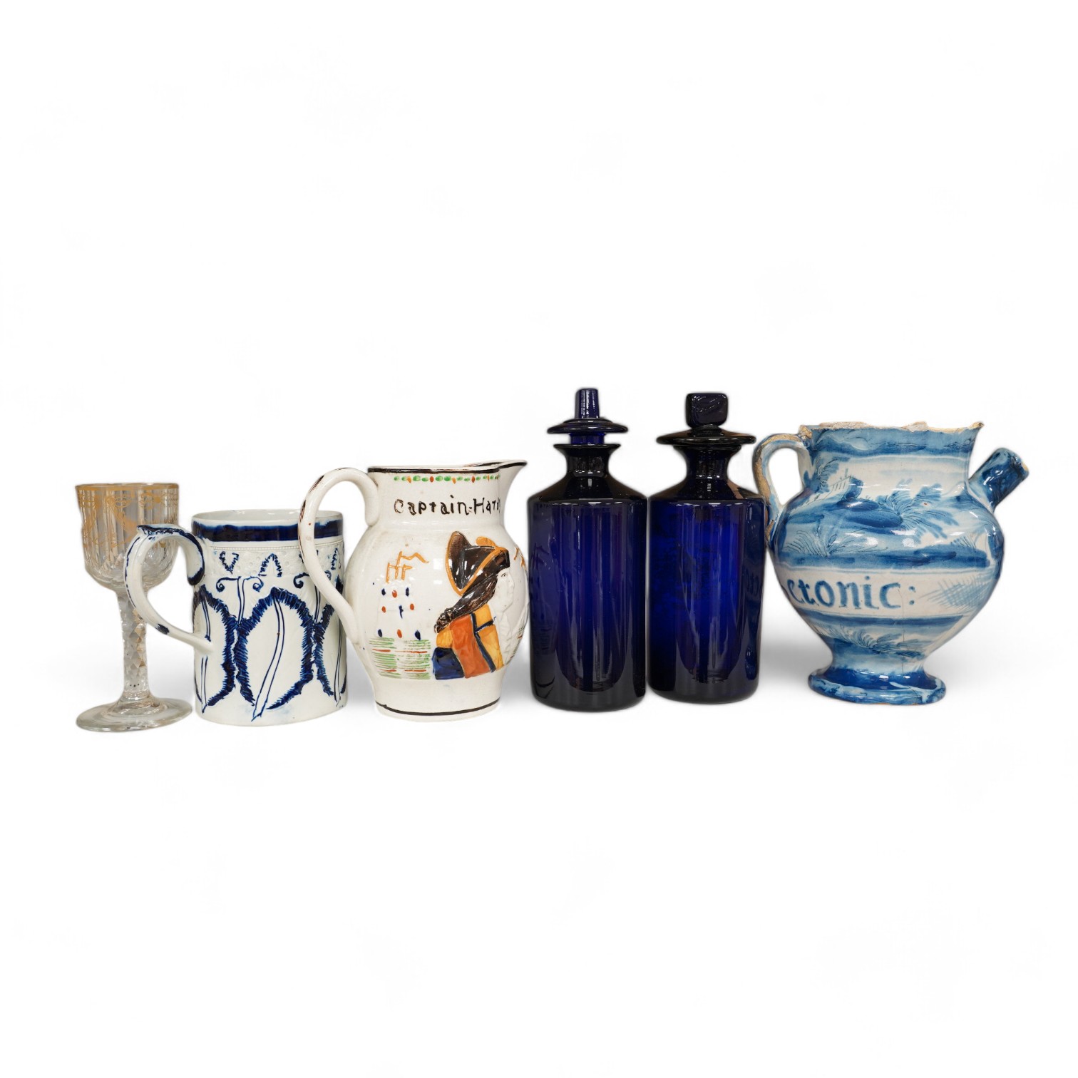 An 18th century pearlware mug, an 18th century Italian maiolica wet drug jar, a faceted wine glass, a commemorative jug and a pair of Bristol blue glass decanters and stoppers, tallest 19cm. Condition - varies